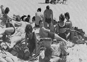 Manhattan College boys and girls lay out in the sun on a beach in 1962
